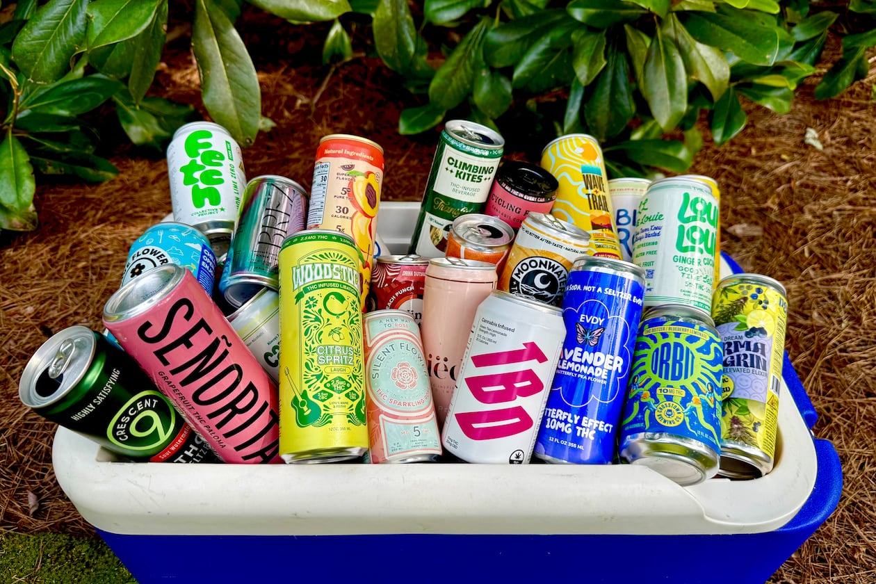 An open cooler is placed on the ground outside. It is overflowing with colorful cans of different cannabis-infused beverages.