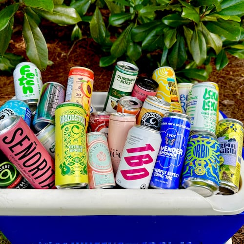 An open cooler is placed on the ground outside. It is overflowing with colorful cans of different cannabis-infused beverages.