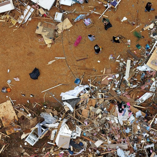 People walk among debris at Gene's Mobile Home Supply, a trailer park in Bogue Chitto, Miss., Thursday, May, 7, 2026, after a tornado cut across the state. (AP Photo/Gerald Herbert)