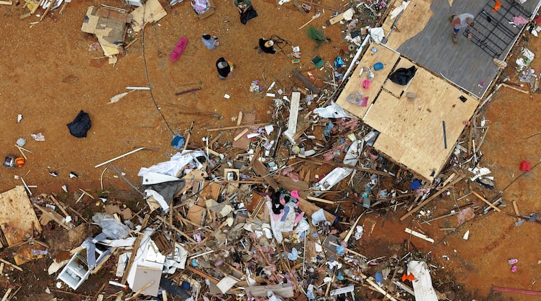 People walk among debris at Gene's Mobile Home Supply, a trailer park in Bogue Chitto, Miss., Thursday, May, 7, 2026, after a tornado cut across the state. (AP Photo/Gerald Herbert)