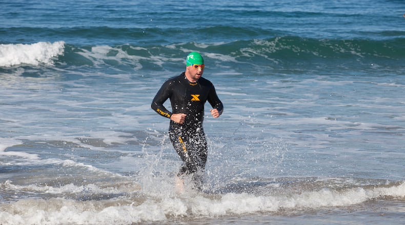 Douglas Mogle bounds out of the Pacific surf during a triathlon a few weeks ago in Malibu. Two years ago, the 33-year-old Canton resident suffered two heart attacks and had a pacemaker installed. Photo Credit: Amanda Sloane