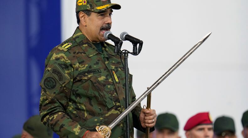 Venezuelan President Nicolas Maduro holds a ceremonial sword said to have belonged to independence hero Simon Bolivar during a government-organized civic-military march in Caracas, Venezuela, Tuesday, Nov. 25, 2025. (AP Photo/Ariana Cubillos)