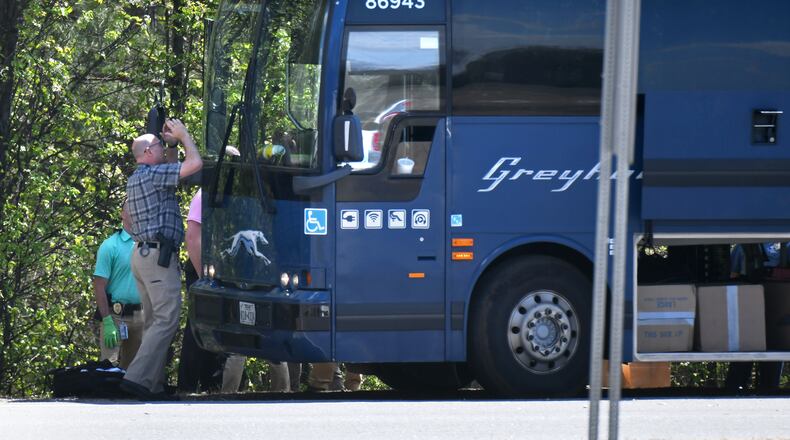 An officer tries to look inside a Greyhound bus through the windshield after an armed man was taken into custody on an I-85 on-ramp in Gwinnett County on Tuesday.