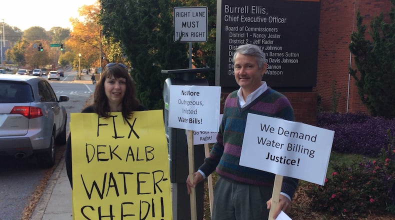 Ellen Buettner and Bill Cox protest DeKalb County’s problem with high water bills outside the Maloof Auditorium on Tuesday. MARK NIESSE / MARK.NIESSE@AJC.COM