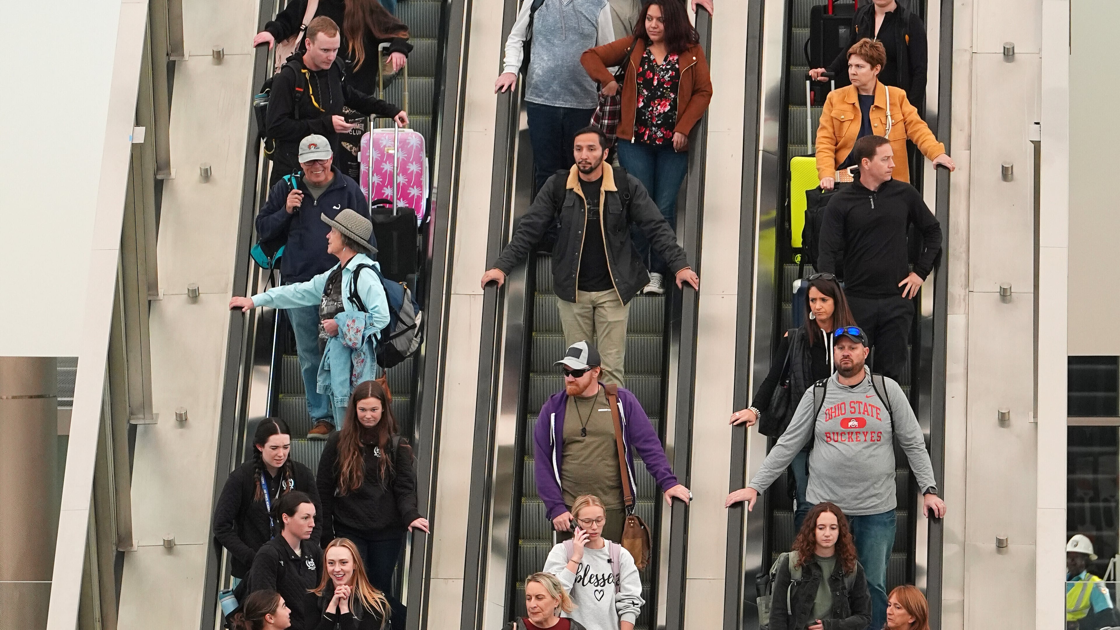 Travellers head down an escalator after clearing through a security checkpoint in Denver International Airport Friday, Nov. 7, 2025, in Denver. (AP Photo/David Zalubowski)