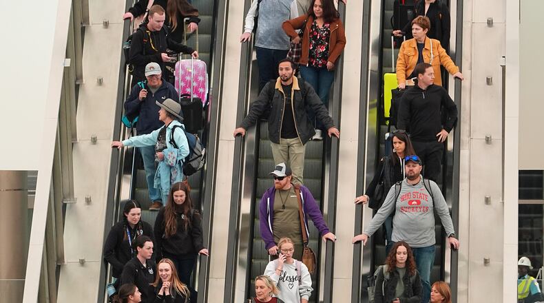 Travellers head down an escalator after clearing through a security checkpoint in Denver International Airport Friday, Nov. 7, 2025, in Denver. (AP Photo/David Zalubowski)
