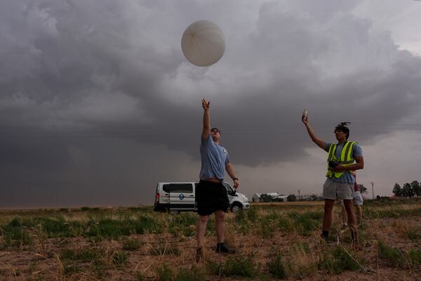 Red team and Project ICECHIP members Wyatt Ficek, left, and Ethan Mok, right, release a latex weather balloon with an attached instrument called a windsond into the inflow region of a storm to collect data during a Project ICECHIP operation Thursday, June 5, 2025, near Morton, Texas. (AP Photo/Carolyn Kaster)