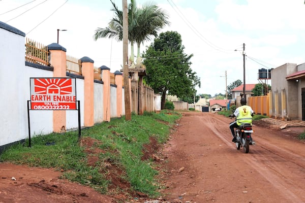 A person rides past a sign for EarthEnable on May 17, 2025, in Jinja, Uganda. (AP Photo/Hajarah Nalwadda)