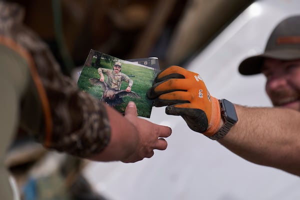 Family friend Melvin Brock, right, finds a photo as he sifts through what is left of Wilson's destroyed home, Sunday, May 18, 2025, in London, Ky., after a severe storm passed through the area. (AP Photo/Carolyn Kaster)