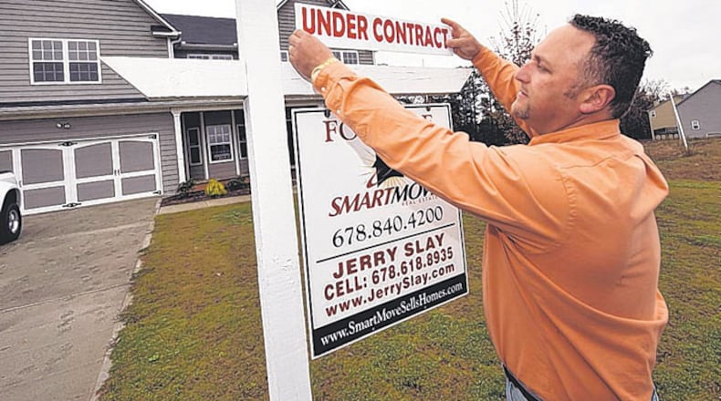 Real estate agent Jerry Slay places an “Under Contract” sign at a house in Douglas County. Many bank-owned homes are selling, fueled by a demand from first-time home buyers.