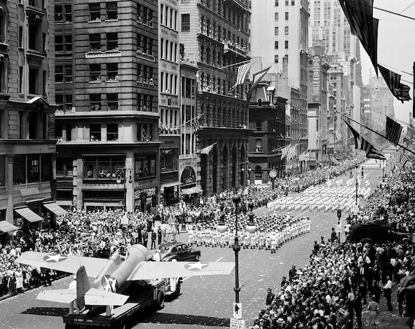 FILE - Thousand of people line streets to cheer on naval units marching on Fifth Avenue in a war parade in New York, June 13, 1942. At lower left is a Grumman "Wildcat" fighter that is flown from U.S. aircraft carriers. (AP Photo, File)