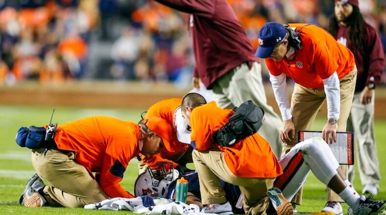 FILE - In this Nov. 19, 2016, file photo, Auburn head coach Gus Malzahn looks on as trainers attend to linebacker Darrell Williams while Alabama A&M head coach James Spady reacts to a targeting call during the first half of an NCAA college football game in Auburn, Ala. College football's most hated rule turns five years old in 2017. Targeting, which penalizes players for hits to the head with ejections, drives coaches, players and especially fans crazy, is here to stay and its supporters are adamant that it is a necessary part of the evolution of college football. (AP Photo/Butch Dill, File)