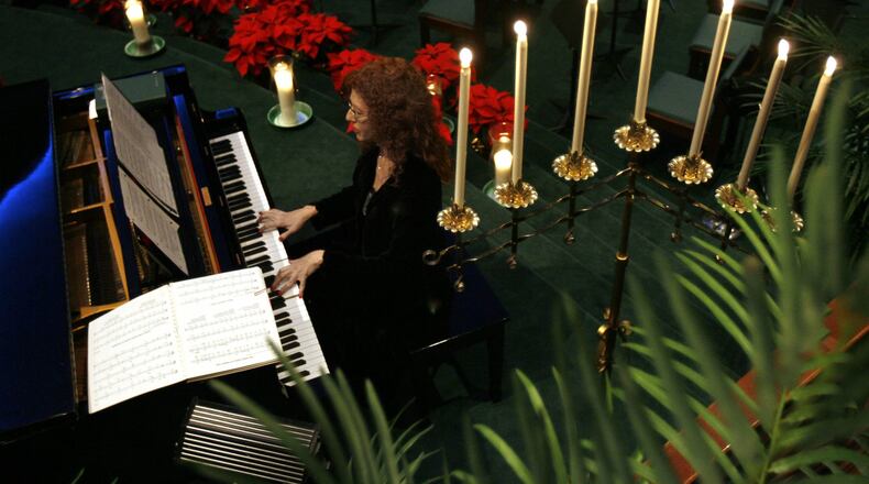 Pianist Brandi Williams plays surrounded by Christmas decorations including several poinsettias during the prelude to the Christmas Eve Communion Service at Mount Carmel Christian Church Wednesday night in Stone Mountain, Ga., December 24, 2008. This is the same church that vandals, earlier this December, destroyed the manger of their drive-through living Nativity scene. JASON GETZ / jgetz@ajc.com