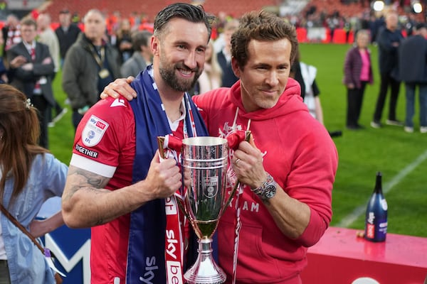 Wrexham co-owner Ryan Reynolds, right, and Wrexham's Ollie Palmer pose with trophy at the end of the English League One soccer match between Wrexham and Charlton Athletic at the Racecourse ground in Wrexham, Wales, Saturday, April 26, 2025. (AP Photo/Jon Super)