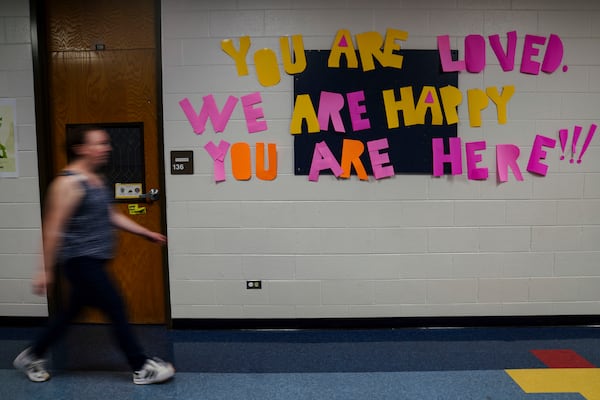 A staff member walks past a message to students that hangs on the wall at Place Bridge Academy, May 20, 2025, in Denver. (AP Photo/Rebecca Slezak)