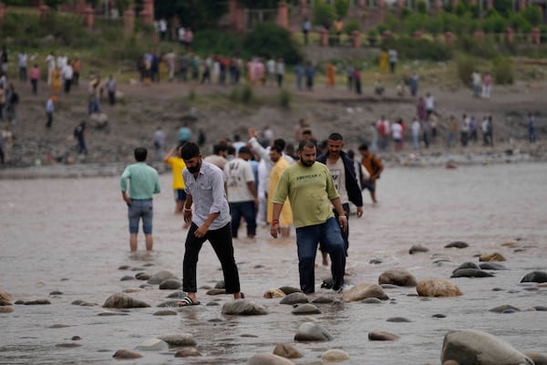 People cross the Chenab River after the flow of water was halted from a dam, at Akhnoor, on the outskirts of Jammu, India, Monday, May 5, 2025. (AP Photo/Channi Anand)