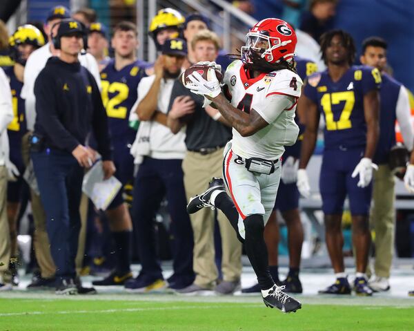 Georgia running back James Cook catches a pass with Michigan head coach Jim Harbaugh watching during the second half at the Orange Bowl at Hard Rock Stadium in Miami Gardens on Friday, Dec. 3`, 2021, in Miami Gardens.   Curtis Compton / Curtis.Compton@ajc.com 
