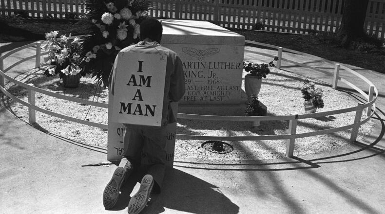 A striking Atlanta sanitation worker kneels at the grave of Dr. Martin Luther King Jr. after a rally by Southern Christian Leadership Conference supporting the strike in Atlanta on April 4, 1970. King was killed in Memphis, Tenn., two years earlier while supporting a sanitation workers’ strike there. The picket signs reading “I Am A Man” were first used in the Memphis strike. (AP Photo/BJ)