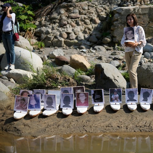 Martha Lucia Lopez holds a boat with a photo of her son Sergio Melendro Lopez missing since the Nevado del Ruiz eruption before the release of small boats with photos of the missing children, into the Guali River in Honda, Colombia, Wednesday, Nov. 12, 2025, on the eve of the 40th anniversary of the disaster that killed about 25,000 people. (AP Photo/Fernando Vergara)
