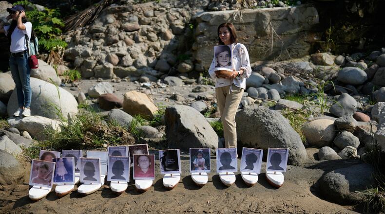 Martha Lucia Lopez holds a boat with a photo of her son Sergio Melendro Lopez missing since the Nevado del Ruiz eruption before the release of small boats with photos of the missing children, into the Guali River in Honda, Colombia, Wednesday, Nov. 12, 2025, on the eve of the 40th anniversary of the disaster that killed about 25,000 people. (AP Photo/Fernando Vergara)