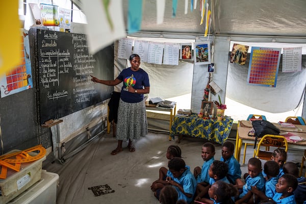 Noellina Tavi teaches elementary students in a tented classroom at Sainte Jeanne D'Arc school in Port Vila, Vanuatu, Thursday, July 17, 2025. (AP Photo/Annika Hammerschlag)