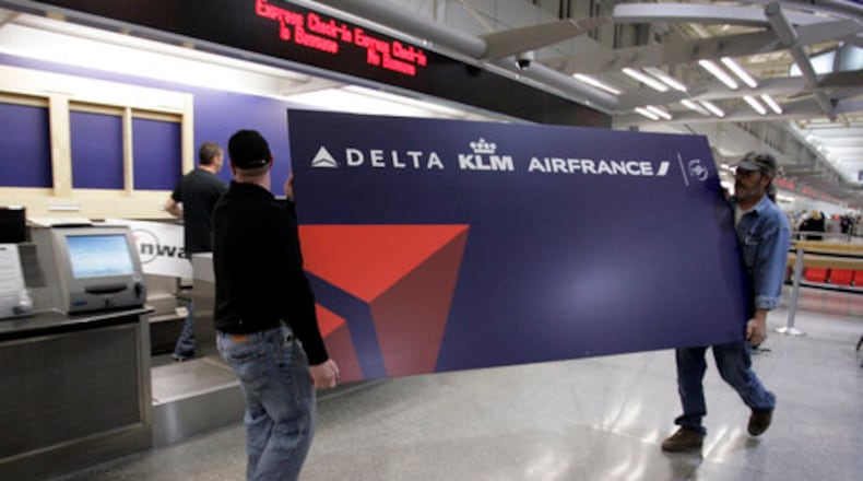 Travelers walking into Minneapolis-St. Paul International Airport on Tuesday saw the Delta Air Lines name splashed across a terminal that was once dominated by Northwest Airlines. Here, Shannon King (left) and Brian Vosberg carry a new Delta sign to a ticket counter Monday.