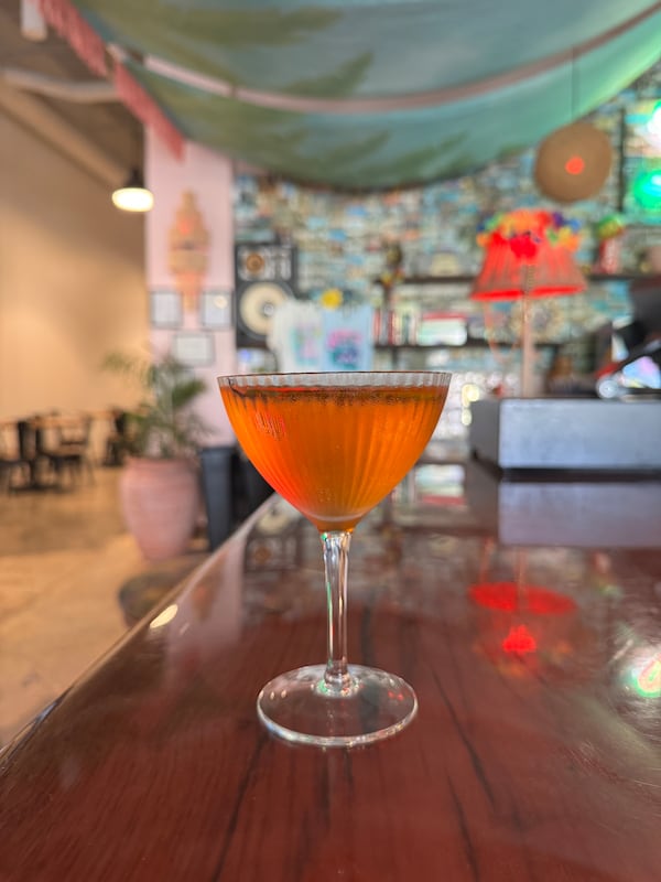 A cocktail in a tall glass without ice, resting on the bar at Strangers in Paradise.