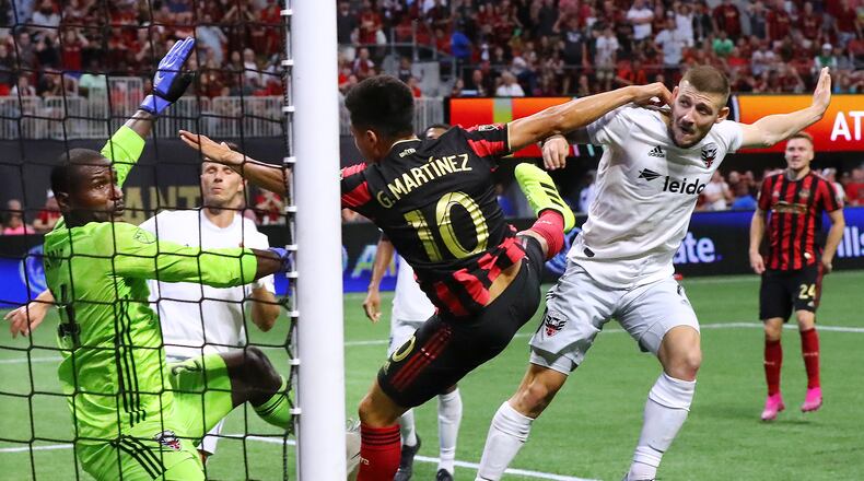 Atlanta United midfielder Pity Martinez scores a goal between D.C. United goalkeeper Bill Hamid and midfielder Paul Arriola for a 1-0 lead in a soccer match on Sunday, July 21, 2019, in Atlanta. Atlanta United won the game 2-0. Curtis Compton/ccompton@ajc.com