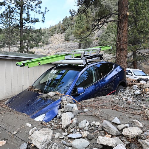 A car is buried in mud after a series of storms Thursday, Dec. 25, 2025, in Wrightwood, Calif. (AP Photo/William Liang)