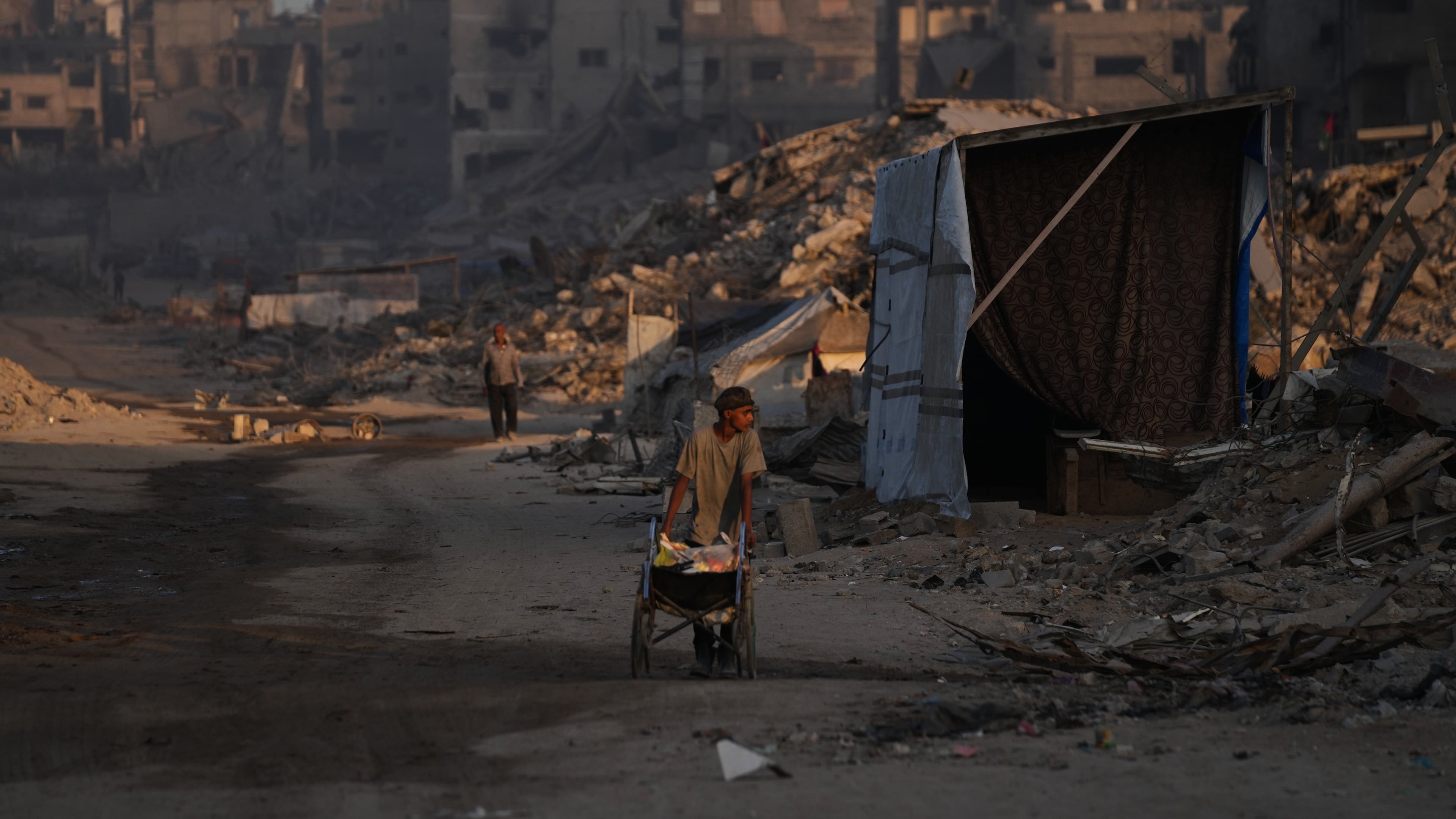 Palestinians walk trough the destruction caused by the Israeli air and ground offensive in Sheikh Radwan neighborhood in Gaza City, Wednesday, Oct. 22, 2025. (AP Photo/Abdel Kareem Hana)