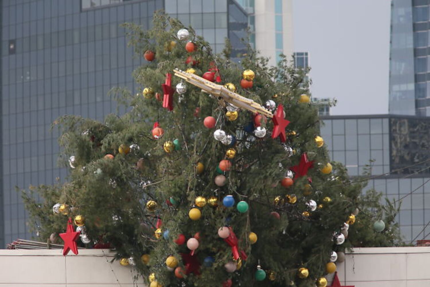 Crane buckles, leaving Christmas tree hanging off roof