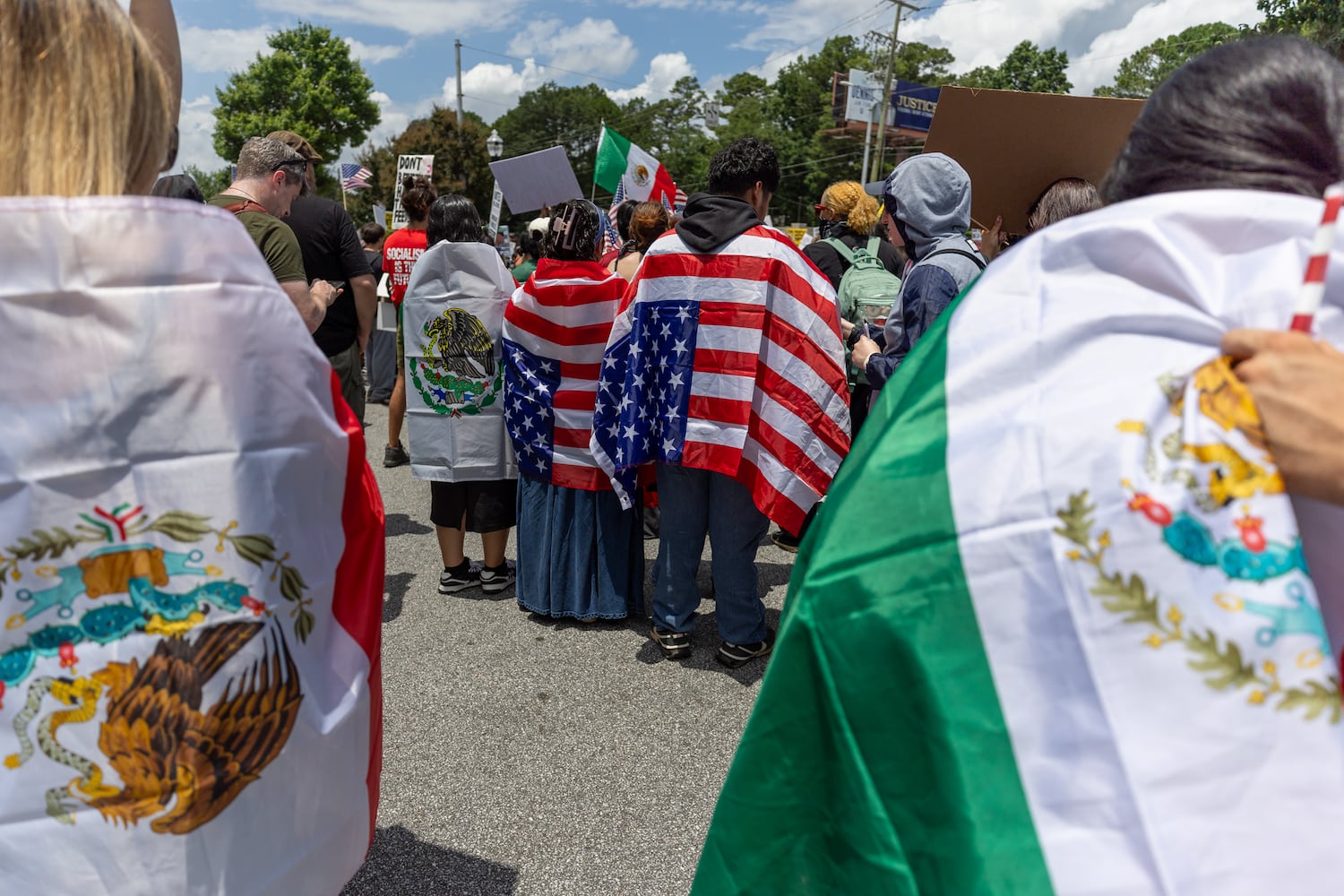 Demonstrators wear Mexican and American flags during a protest on ICE raids and deportation arrests on Chamblee Tucker Road in Atlanta on Saturday, June 14, 2025. (Arvin Temkar / AJC)