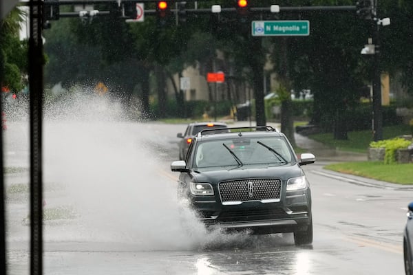 A vehicle drives through a partially flooded street Tuesday, July 15, 2025, as tropical weather moves over Orlando, Fla. (AP Photo/John Raoux)