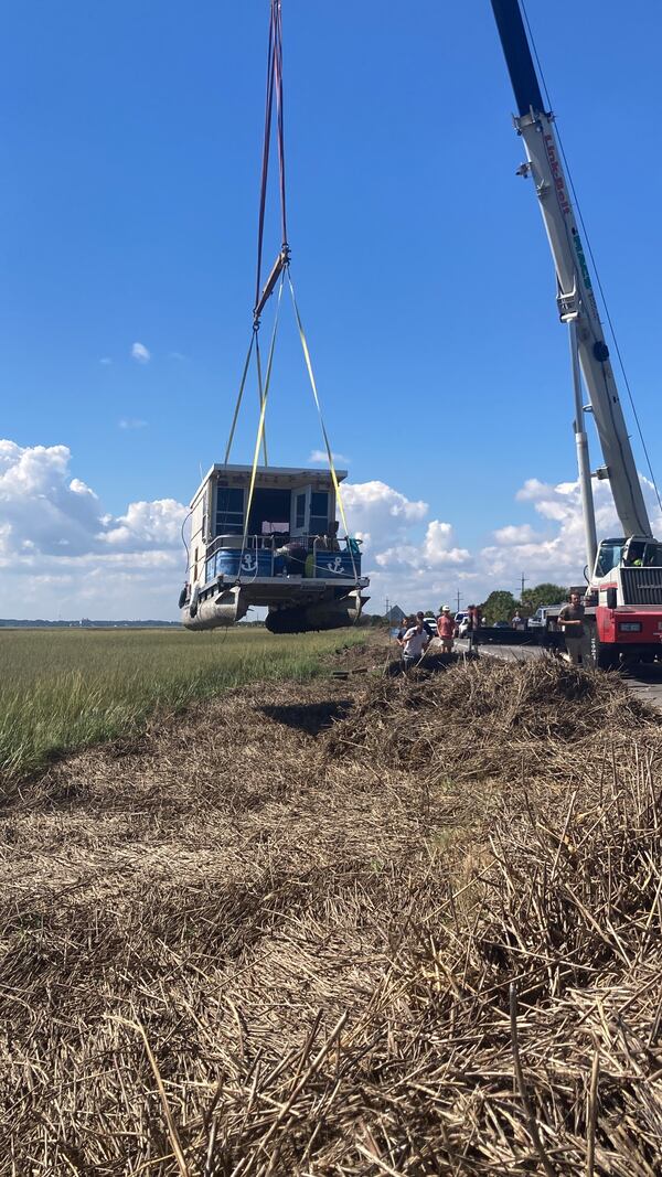 A crane operator removes Castaway from where the boat had run aground during Hurricane Helene. The crane later refloated the vessel at a nearby boat ramp. (Adam Van Brimmer/AJC)