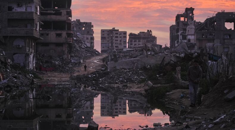 Palestinians walk amid buildings destroyed by Israeli air and ground operations in Gaza City, Thursday, Jan. 29, 2026. (AP Photo/Jehad Alshrafi)