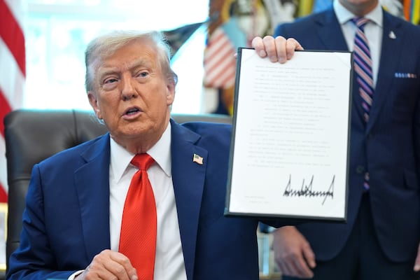 President Donald Trump — pictured holding up a signed executive order last week regarding flag burning — signed an executive order in September that imposed a $100,000 application fee on H-1B visas to be paid by employers. (Evan Vucci/AP)