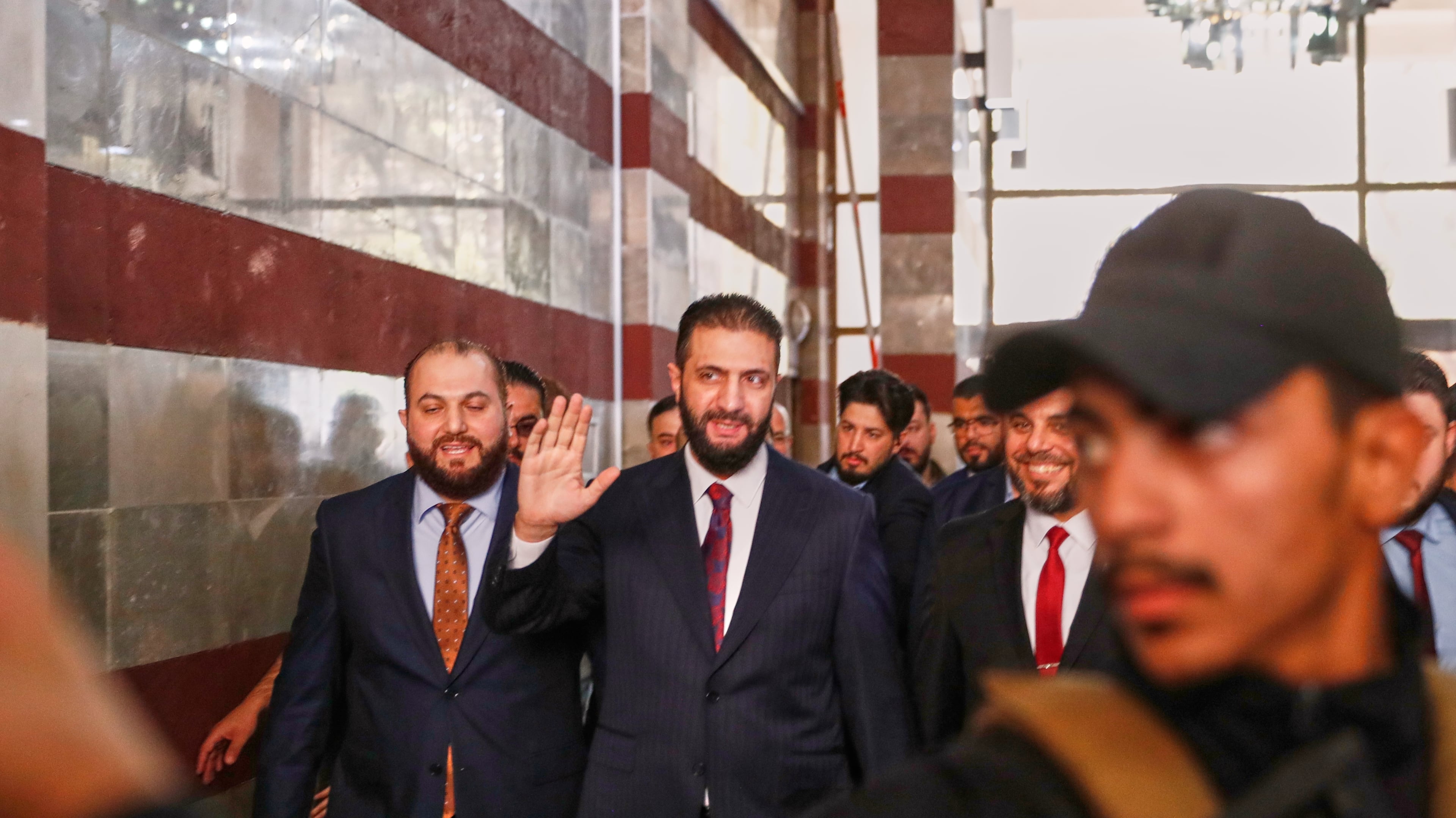 Syrian interim President Ahmad al-Sharaa waves as he enters a polling station where electoral college members are voting in a parliamentary election in Damascus, Syria, Sunday, Oct. 5, 2025. (AP Photo/Omar Sanadiki)