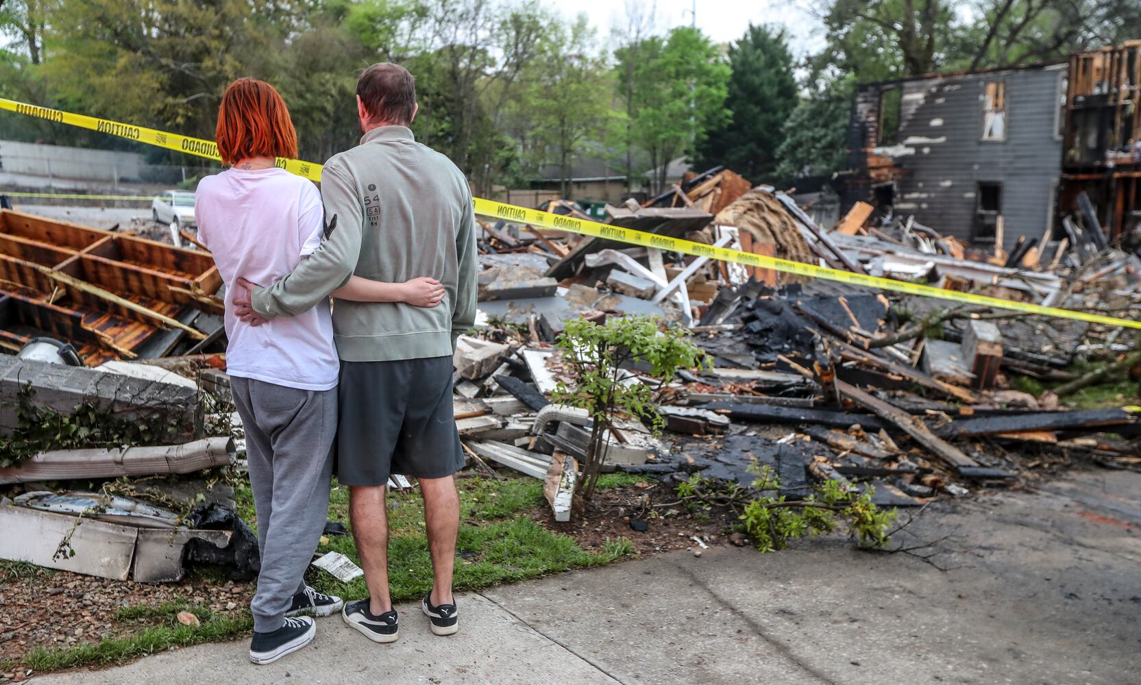 Kristen Sanchez (left) stands with resident and boyfriend Nikolas Waldschuetz in front of what was Waldschuetz's apartment for the last five years. Firefighters returned overnight into Monday morning, April 3, 2023, to keep water on the smoldering remains of the North High Ridge Apartments on North Avenue, where a least 28 people were left without a home Sunday morning. (John Spink / John.Spink@ajc.com)

