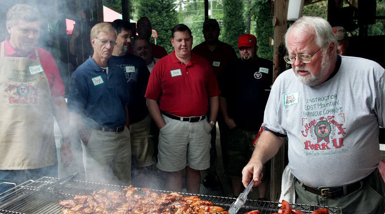 Sam Huff (right) grills some sausage and chicken wings after smoking them during his Lost Mountain Barbecue Company College of Pig Knowledge class a/k/a PorkU. AJC file
