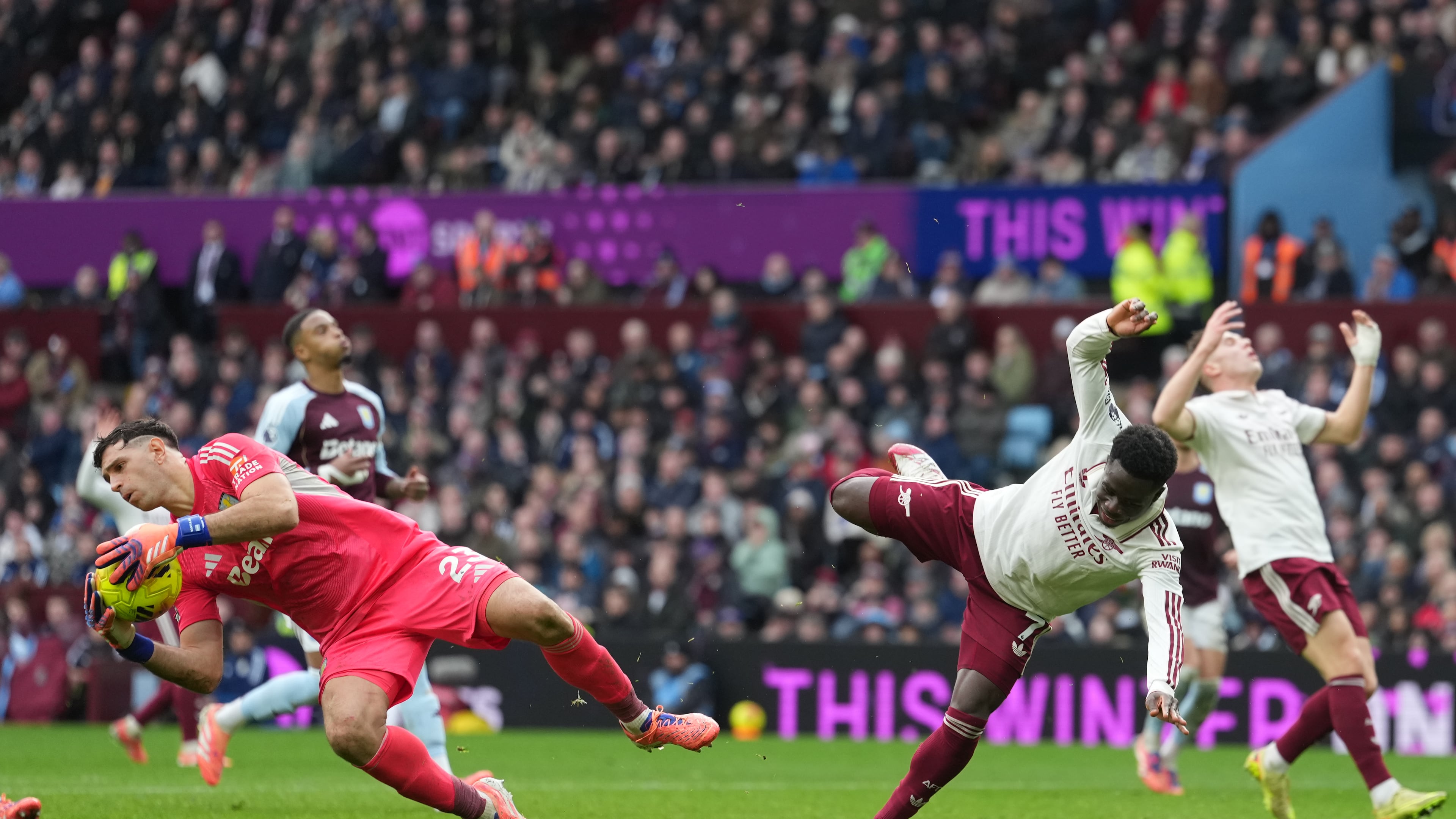 Aston Villa's goalkeeper Emiliano Martinez, left, makes a save ahead of Arsenal's Bukayo Saka during the English Premier League soccer match between Aston Villa and Arsenal in Birmingham, England, Saturday, Dec. 6, 2025. (AP Photo/Dave Shopland)