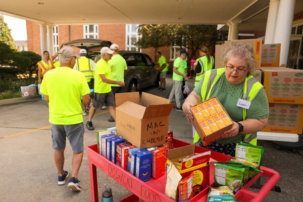 Volunteer Laura Smith, right, works with others during the weekly drive-up food pantry at First Presbyterian Church in Marietta. A few hundred families come through to pick up food each Tuesday. (Jason Getz/AJC)