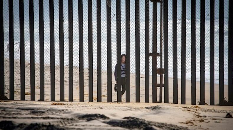 A person from Tijuana in Mexico peers through the border fence at the Border Field State Park on April 14, 2016 in Imperial Beach, Calif. (LiPo Ching/Bay Area News Group/TNS)