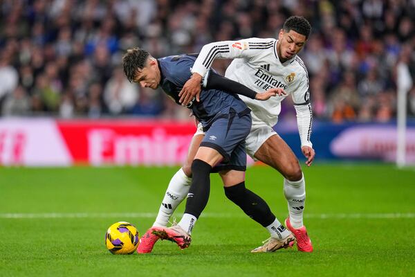 Rayo's Andrei Ratiu, left, challenges for the ball with Real Madrid's Jude Bellingham during the Spanish La Liga soccer match between Real Madrid and Rayo Vallecano at the Santiago Bernabeu stadium in Madrid, Spain, Sunday, March 9, 2025. (AP Photo/Manu Fernandez)