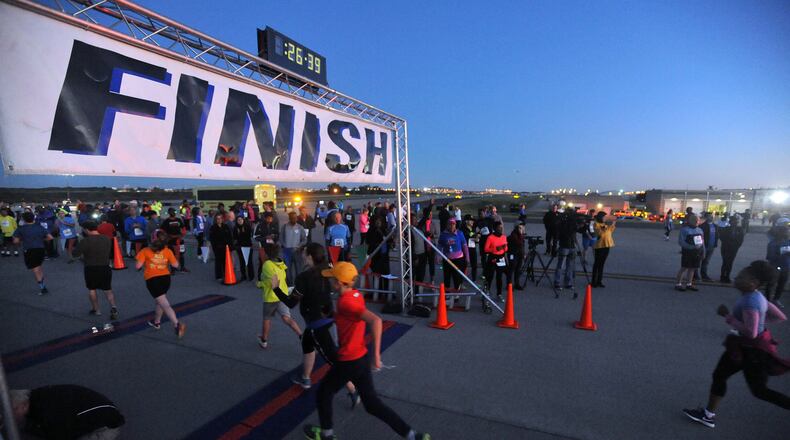 Runners cross the finish line in the inaugural 5K on the 5th Runway. The race will be run again this year after a hiatus because of the COVID-19 pandemic. KENT D. JOHNSON/KDJOHNSON@AJC.COM