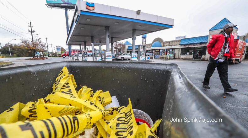 Discarded crime scene tape sits at a Chevron gas station on the corner of Pryor Road and University Avenue in southwest Atlanta, where three people were shot Wednesday night.