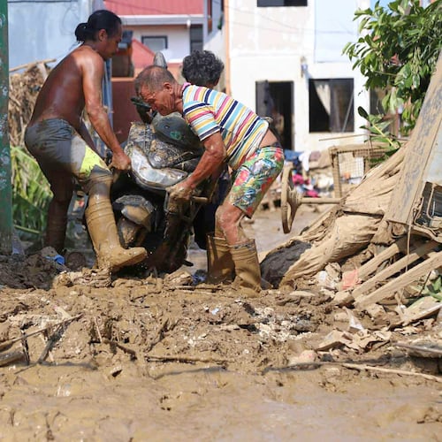 Residents carry a motorcycle along a muddied street caused by Typhoon Kalmaegi, in Liloan, Cebu province, central Philippines on Thursday, Nov.6, 2025. (AP Photo/Jacqueline Hernandez)