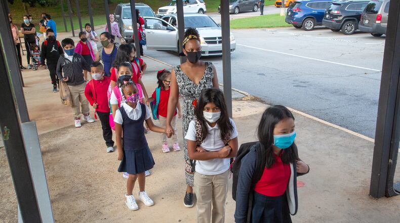 Parents and their children line up to enter Lake City Elementary in Morrow on the first day of school, Monday, August 2, 2021. Clayton County school district is requiring masks for staff and students this school year. STEVE SCHAEFER FOR THE ATLANTA JOURNAL-CONSTITUTION