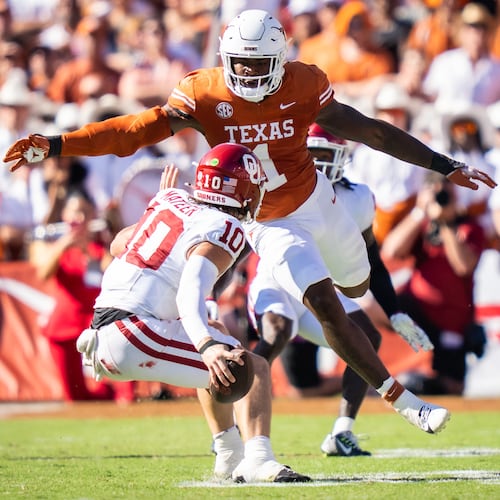 FILE - Texas linebacker Colin Simmons (1) goes to tackle Oklahoma Sooners quarterback John Mateer (10) during the second quarter of an NCAA college football game at the Cotton Bowl in Dallas, Oct. 11, 2025. (Sara Diggins/Austin American-Statesman via AP, File)