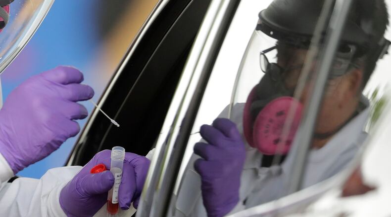 Christopher Ikemire prepares to test a customer at the Eastern Star Church, Thursday, April 30, 2020, in Indianapolis. Indianapolis city, health and faith leaders set-up the new COVID-19 testing site in the city's most vulnerable neighborhoods. The new coronavirus causes mild or moderate symptoms for most people, but for some, especially older adults and people with existing health problems, it can cause more severe illness or death. (AP Photo/Darron Cummings)