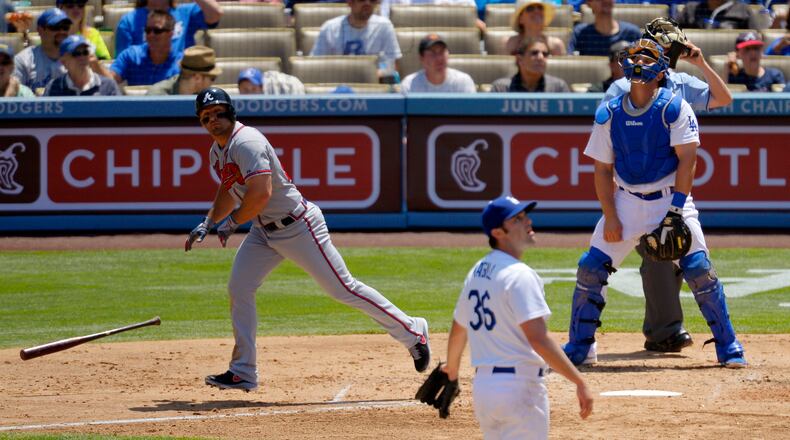 Atlanta Braves' Dan Uggla, left, hits a three-run home run as Los Angeles Dodgers starting pitcher Matt Magill, center, and catcher Tim Federowicz look on during the third inning of their baseball game, Sunday, June 9, 2013, in Los Angeles.